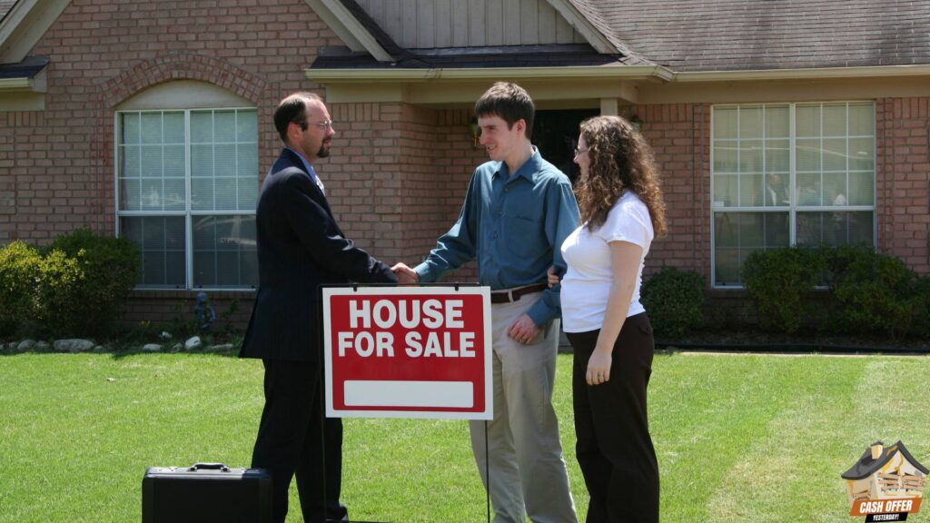 Buyer and couple shaking hands in front of a 'House For Sale' sign, with a house in the background, signifying a successful real estate transaction. We Buy Houses in Dallas TX.