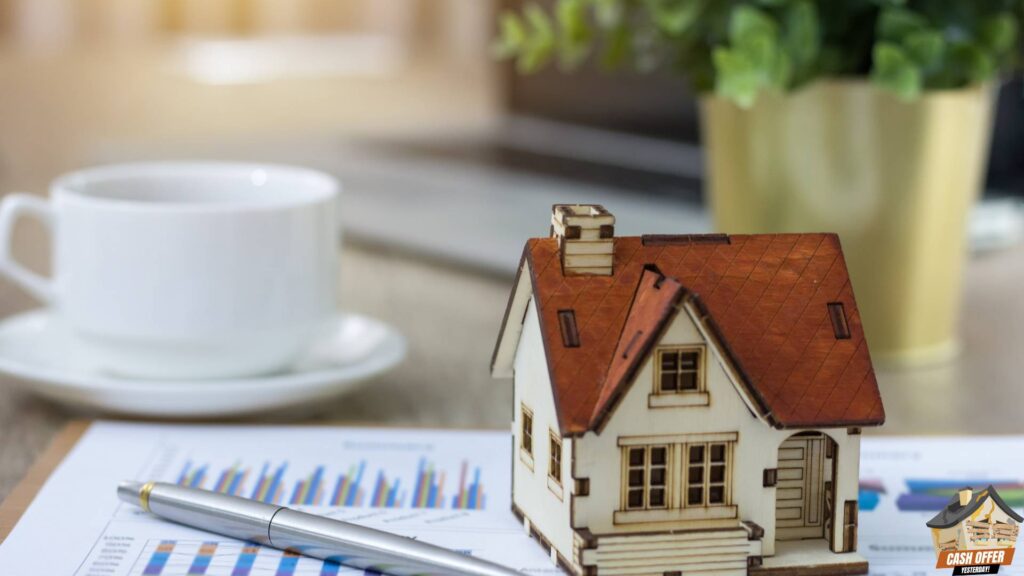 Miniature house model, pen, and coffee cup on a table, symbolizing real estate transactions and home selling. We Buy Houses in Dallas TX.