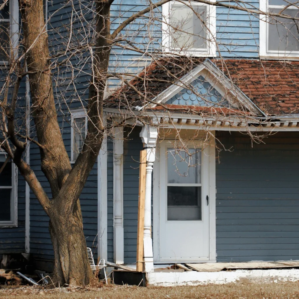 Photo of a house with a leafless tree beside it.